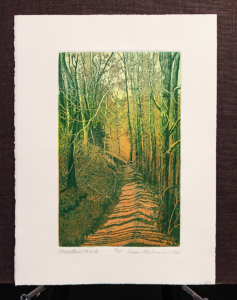 Print titled 'Mountain Walk' showing a sunlit forest path winding between tall, bare trees with green and orange tones in an artful woodland scene.